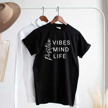 Load image into Gallery viewer, Black tshirt hanging on clothes rack with the words positive vibes, positive mind, positive life