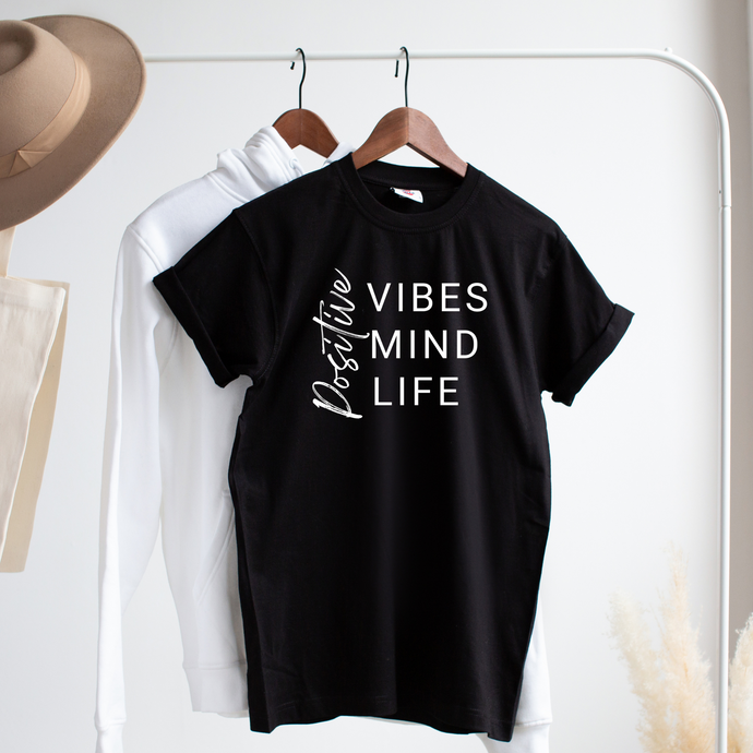 Black tshirt hanging on clothes rack with the words positive vibes, positive mind, positive life